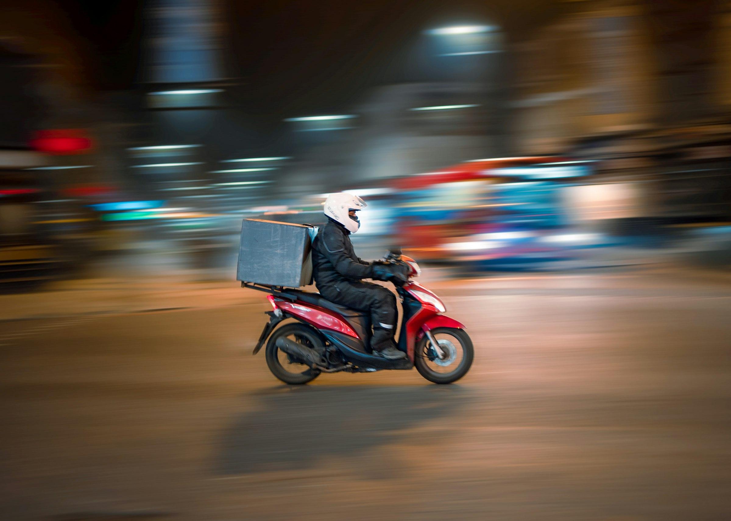 Mensajero en moto realizando una entrega urbana